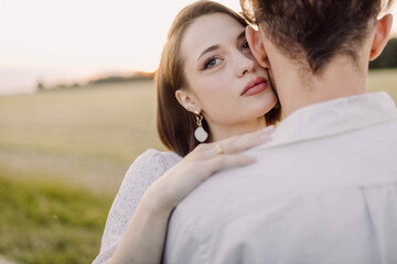 Obraz premium couple in love on a date in nature hugging in a white outfit in the summer. Love, happiness of a young Caucasian couple.