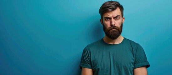 Bearded young man with volunteering t-shirt appears skeptical, nervous, frowning upset due to a problem.