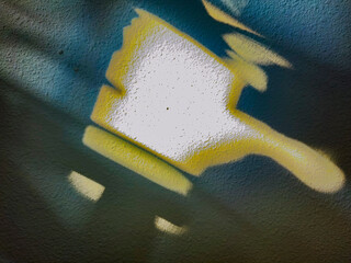 A decorator paintbrush is seen on a stucco wall. It is formed by light & shadow and appears to be a...