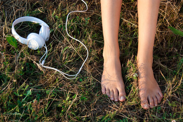 Bare female feet  on a grass and headphones