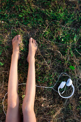 Bare female legs on a grass and headphones