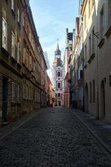 Fototapeta na wymiar Cobbled street and historic belfry of a baroque church in the city of Poznan