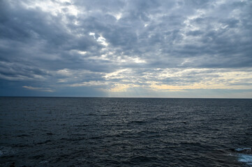 Stormy weather at the sea, view from a boat. Waves on the sea with dramatic clouds above. Rainy winter day. 