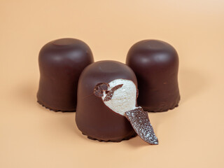 Marshmallows in chocolate glaze on an orange background. Marshmallow close-up.