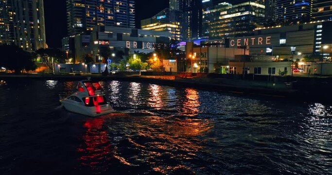 Motor boat going by the river at night. Buildings full of lights on the waterfront of Miami, Florida, USA.