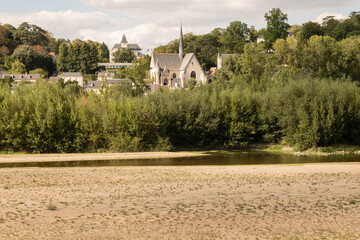 Chapel Église Saint-Cyr et Sainte-Julitte and diminished river Loire in rural France city Tours. fresh waterway has dried up significantly due to dry summer raised temperatures global warming - 703549275