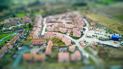 Naklejka premium Aerial view of a suburban neighborhood with tilt-shift effect, creating a miniature scene appearance.