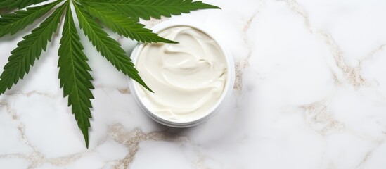 Obraz na płótnie Canvas Organic hemp cream near cannabis leaves on a marble table. Cosmetic mockup, eco-friendly skincare product.