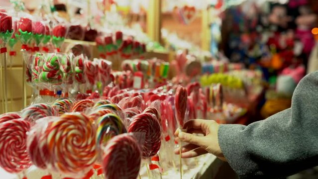 young blonde woman reaching for sweets at a kiosk at a Christmas market