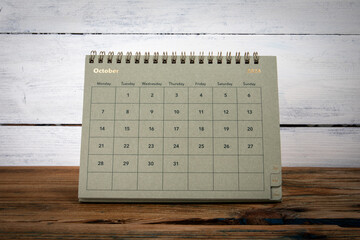 OCTOBER 2024 cardboard desk calendar and planner on a wooden texture table
