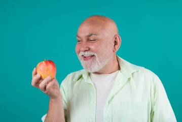 Senior granddad eat apple in studio. Portrait of a elderly man eating an apple. Man biting apple. Apple fruit for aged people. Senior on diet and healthy lifestyle. Studio portrait senior with apples.