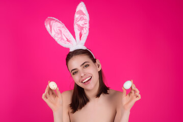 Obraz na płótnie Canvas Portrait of lovely, romantic young woman in rabbit ears celebrating easter holiday, studio background. Holidays party concept. Cheerful girl celebrating Easter in rabbit ears, holding painted eggs.