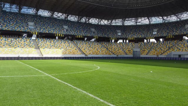 Empty sports and football stadium with nobody, aerial shot football field. Travelling in through the grass