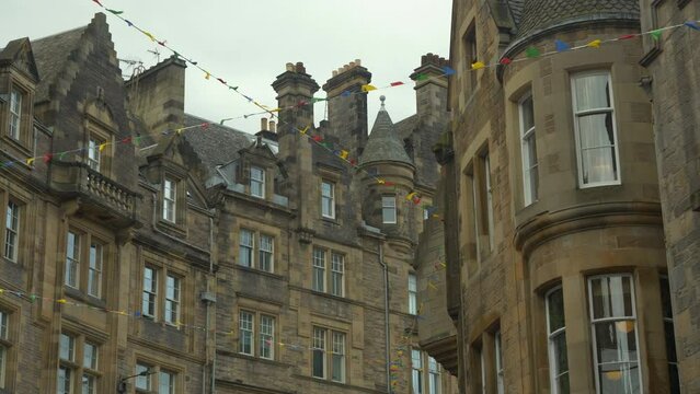 Brightly coloured flags hanging across the street between old stone townhouses. Beautiful facades of historical buildings and bunting flags fluttering in gentle wind. Festive mood in historic city.