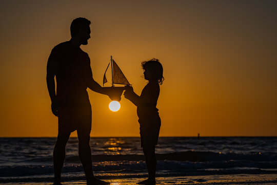 Father and son dream on travel. Father and son enjoying sunset play toys sailing boat. Summer travel, family holidays. Journey trip lifestyle marine concept. Parenting, fatherhood and fathers day.