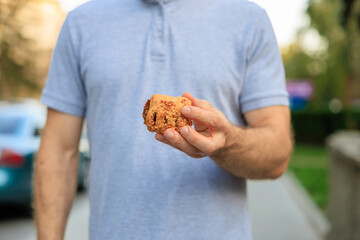 A man's hand holds sweet pastry with jam, snack and fast food concept. Selective focus on hands with blurred background