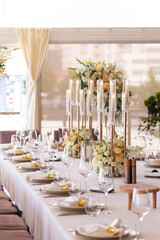 Serving the festive table at a wedding event. Decorating the wedding table with bouquets of flowers. Cutlery at a party 