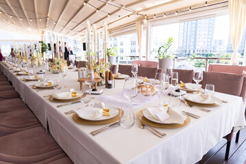 Serving the festive table at a wedding event. Decorating the wedding table with bouquets of flowers. Cutlery at a party 