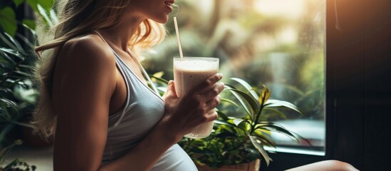 Fit, energized pregnant woman over 40 enjoying protein shake for healthy pregnancy, prioritizing wellness for baby and mom. - obrazy, fototapety, plakaty