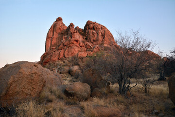 Large boulders are scattered along the rocky mountain slope. Blue sky above