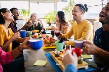 Smiling group of diverse friends having breakfast and talking at coffee bar restaurant - Happy millennial multiracial people having fun together while drinking cappuccino. Friendship concept - obrazy, fototapety, plakaty