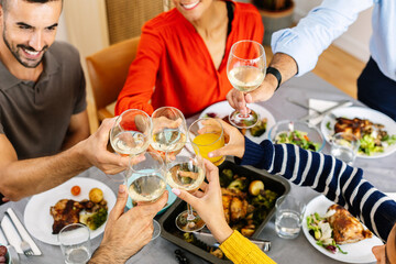 Happy multigenerational family toasting white wine celebrating together at dinner home party