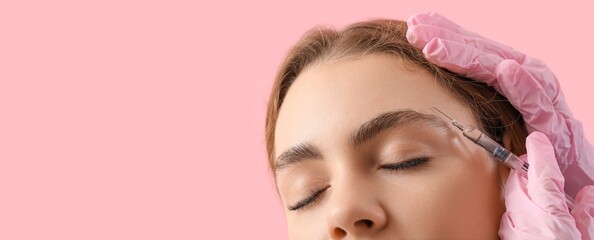 Young woman receiving filler injection in face against pink background with space for text, closeup