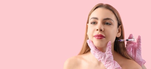 Young woman receiving filler injection in face against pink background with space for text
