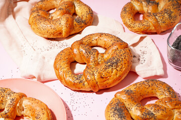 Tasty pretzels with poppy seeds on pink background