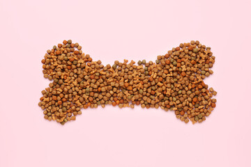 Bone made of dry pet food on pink background