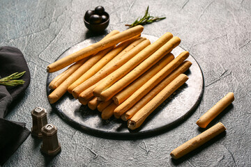 Slate board with tasty Italian Grissini on dark background