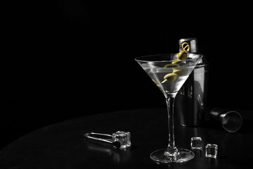 Glass of tasty martini, ice cubes and olives on black background