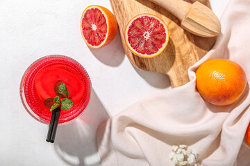 Glass of tasty blood orange lemonade and fresh fruits on light background