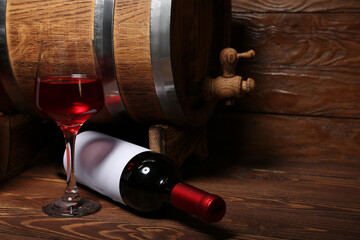 Oak barrel with bottle and glass of wine on wooden background