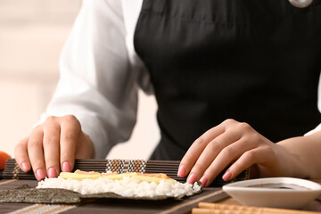 Woman preparing delicious sushi rolls, closeup