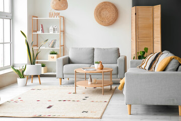 Interior of light living room with grey sofas and wooden coffee table