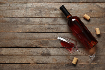 Glass and bottle of red wine on wooden background