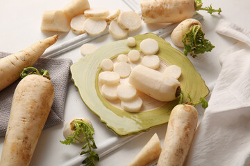 Plate with fresh daikon radishes on white background