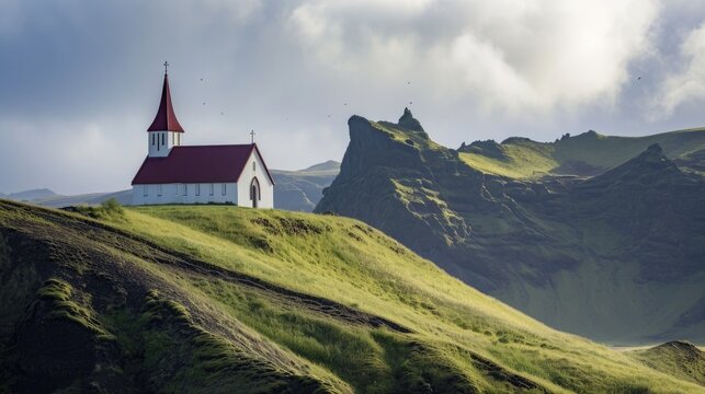 A picturesque white church with a red roof sits atop a green hill. This image can be used to depict serenity, spirituality, or a scenic landscape