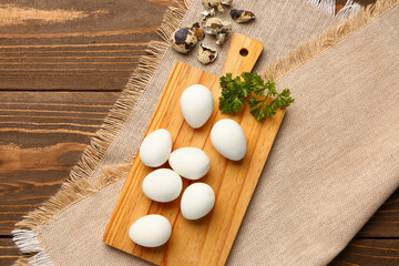 Board of boiled quail eggs with shells on wooden background