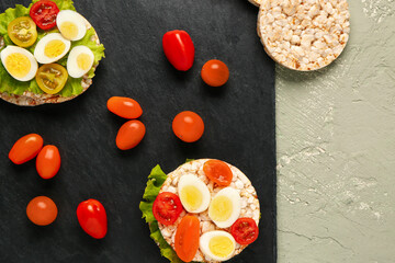 Rice crackers with quail eggs, tomatoes and lettuce on color background