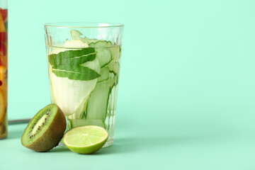 Glass of infused water with different fruits on turquoise background