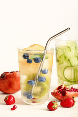 Glasses of infused water with different sliced fruits on white table