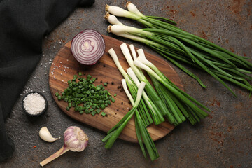 Board with slices of fresh scallion and onion on dark background