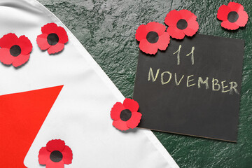 Poppy flowers with flag of Canada and card on grunge dark green background. Remembrance Day