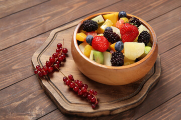 Bowl of fresh fruit salad on wooden background