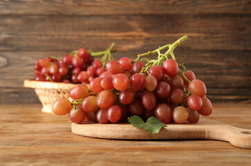 Board with tasty ripe grapes on wooden background - obrazy, fototapety, plakaty