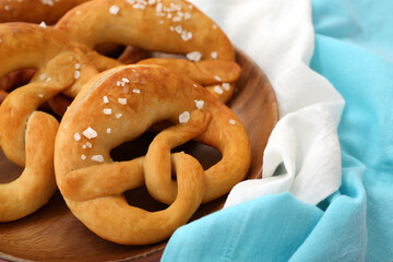 Wooden plate with soft pretzels on table, closeup