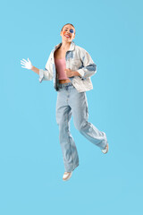 Young woman with painted face jumping on blue background