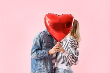 Happy young couple with beautiful heart-shaped balloon on pink background. Valentine's Day...